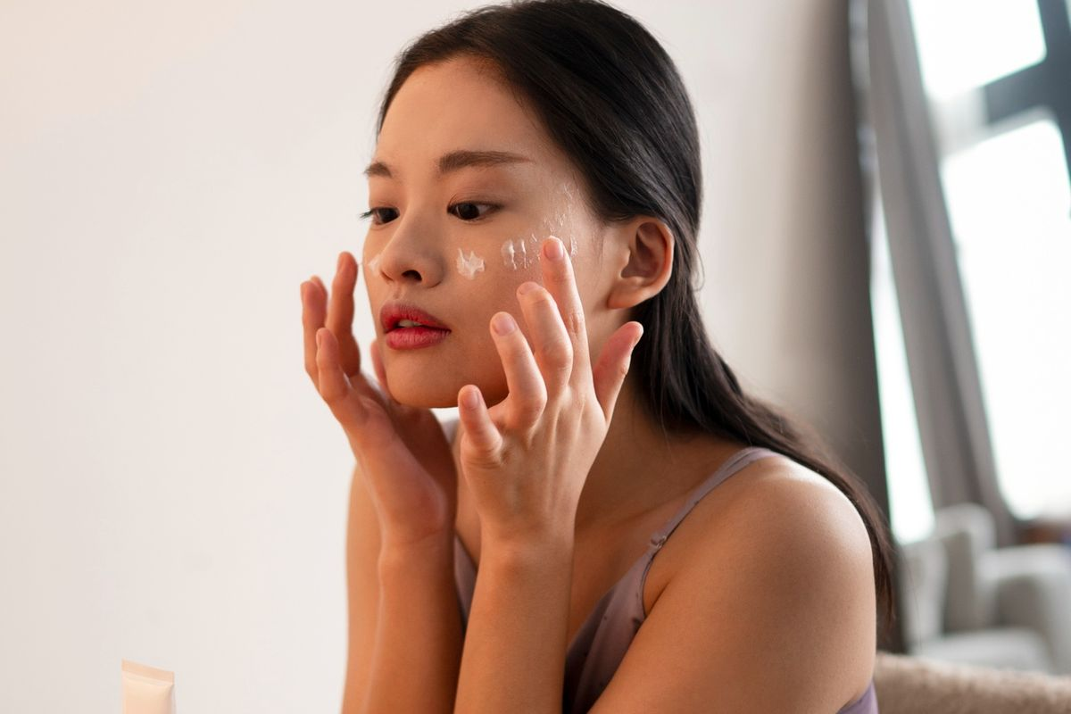 Ilustrasi seorang wanita mengoleskan krim perawatan wajah untuk membantu mengatasi melasma dan menjaga kesehatan kulit.