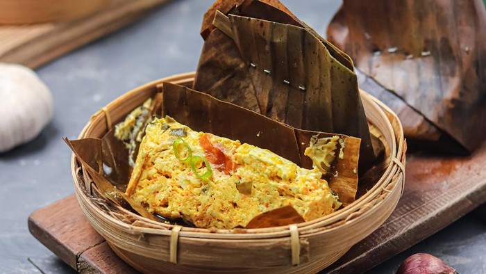 Pepes tahu udang kemangi yang dibungkus daun pisang dan disajikan hangat dengan cita rasa gurih pedas.